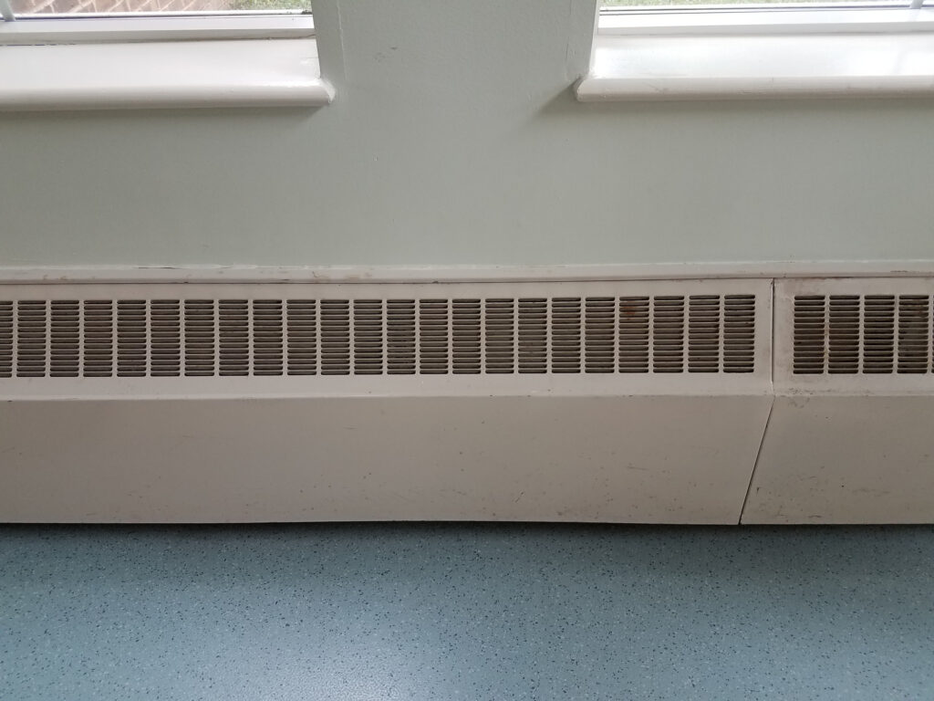 baseboard heating vents and a blue floor underneath windows