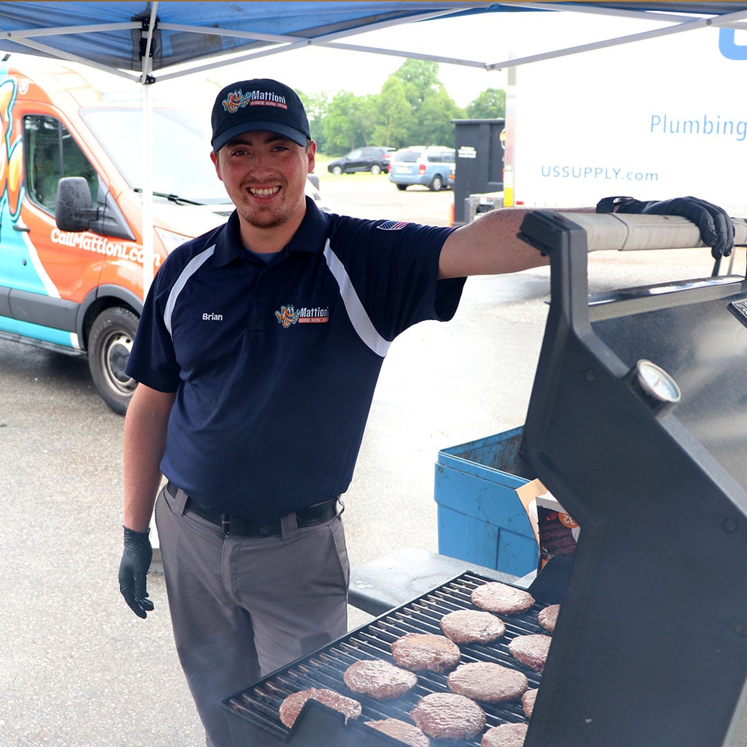 Mattioni employee manning a grill full of cooking burgers