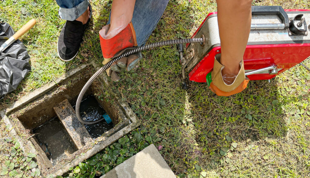 Clearing an outside drain blocked with fat with a electric plumber's snake